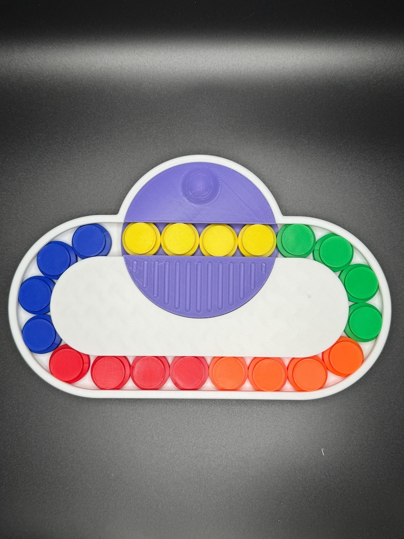 May include: A white cloud-shaped fidget toy with a purple center and a row of yellow buttons. The outer edge of the toy has a circle of blue, red, and green buttons.