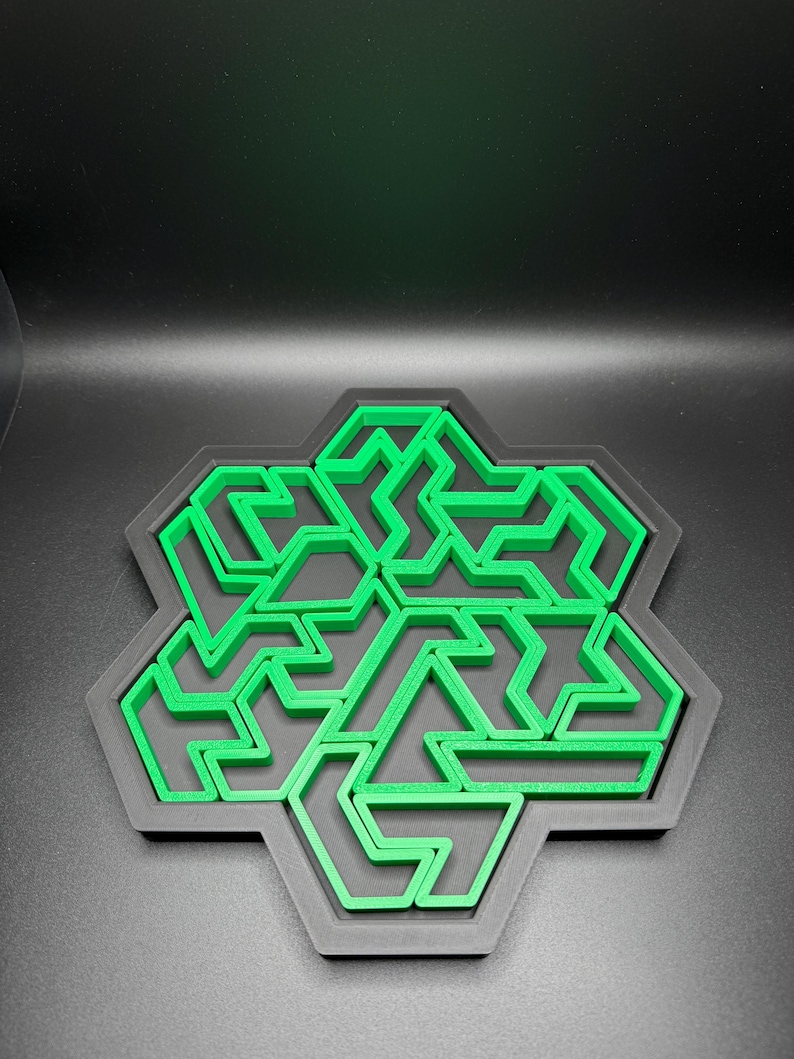 May include: A green 3D printed snowflake design with a black background. The snowflake is made up of a series of interlocking shapes.