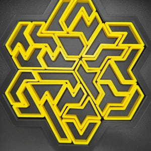 May include: A yellow and black geometric design with a hexagonal shape. The design is made up of multiple interlocking shapes.