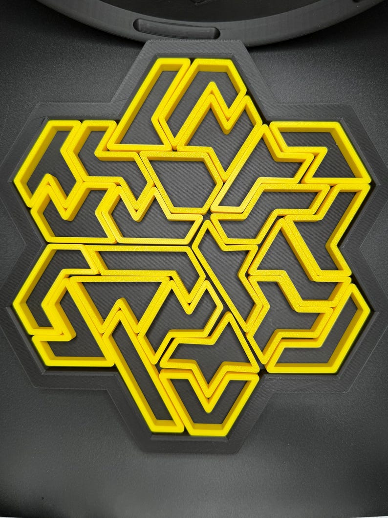 May include: A yellow and black geometric design with a hexagonal shape. The design is made up of multiple interlocking shapes.