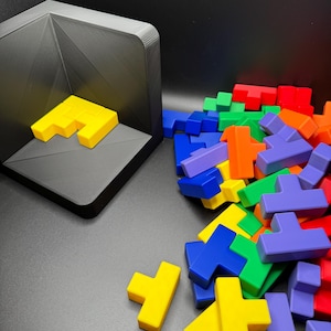 May include: A pile of colorful plastic Tetris-like puzzle pieces in blue, green, yellow, orange, and purple. Some pieces are laying flat, while others are standing upright.