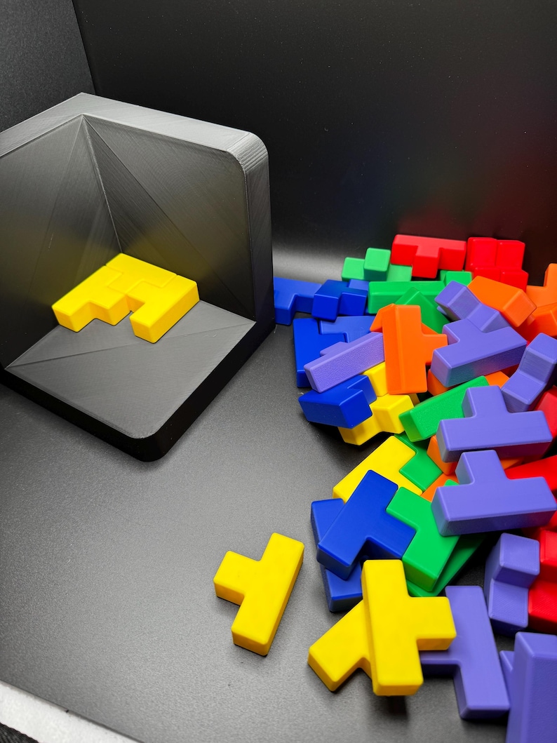 May include: A pile of colorful plastic Tetris-like puzzle pieces in blue, green, yellow, orange, and purple. Some pieces are laying flat, while others are standing upright.