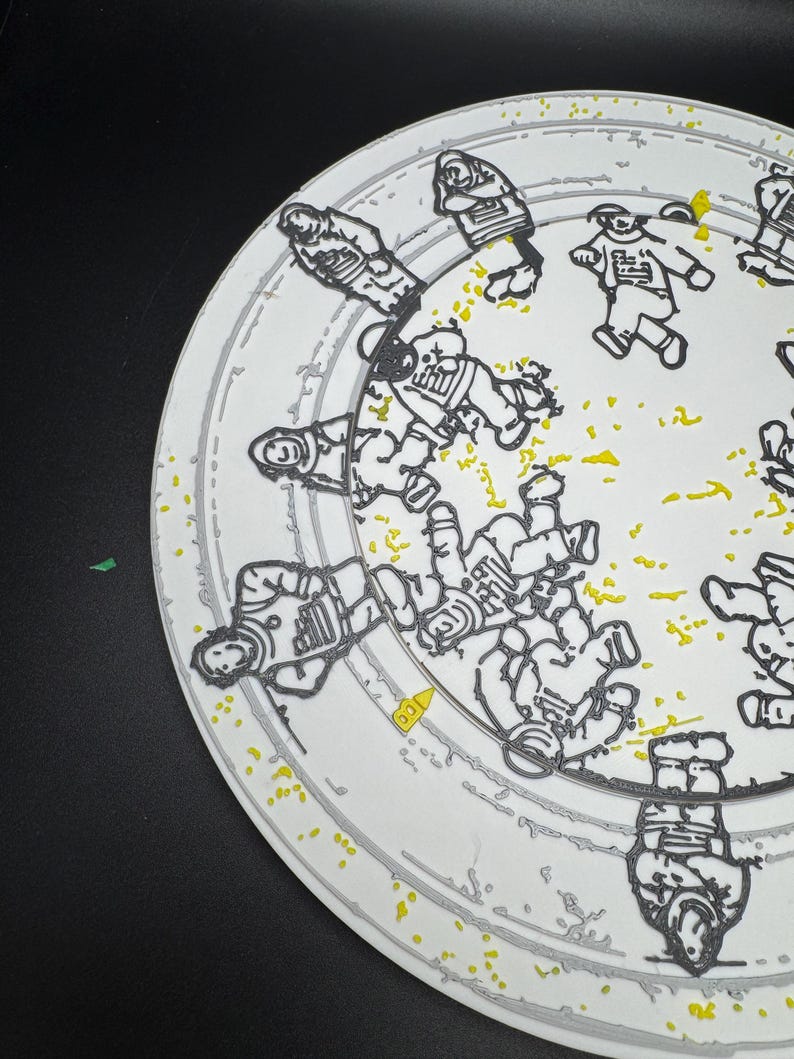 Puede incluir: Plato de cer&aacute;mica blanco con un dise&ntilde;o de astronauta negro y amarillo. El plato presenta m&uacute;ltiples figuras de astronautas en un patr&oacute;n circular, con motas amarillas y un borde gris. El dise&ntilde;o es una representaci&oacute;n art&iacute;stica y l&uacute;dica de la exploraci&oacute;n espacial.