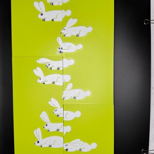 May include: A set of nine white rabbit illustrations on a bright yellow background. The rabbits are in various poses, with some lying down and others standing up. The illustrations are simple and whimsical.