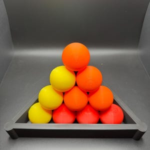 Peut inclure: Une pyramide de boules color&eacute;es dans un support triangulaire. Les boules sont rouges, orange et jaunes.