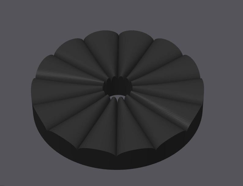May include: A dark gray, circular object with a central hole. The object is composed of multiple, evenly spaced, cone-shaped segments, creating a radial pattern. The design has a three-dimensional appearance, with subtle shading to define the forms.