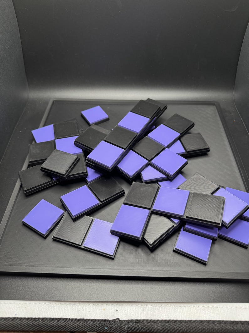 Puede incluir: Un conjunto de baldosas cuadradas negras y moradas, algunas dispuestas en un patr&oacute;n de tablero de ajedrez. Las baldosas est&aacute;n dispersas sobre una superficie oscura, creando un dise&ntilde;o geom&eacute;trico. La combinaci&oacute;n de colores es un contraste de negro y morado claro.