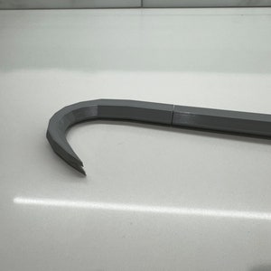 May include: A gray metal crowbar with a curved end. The crowbar is made of metal and has a textured surface.