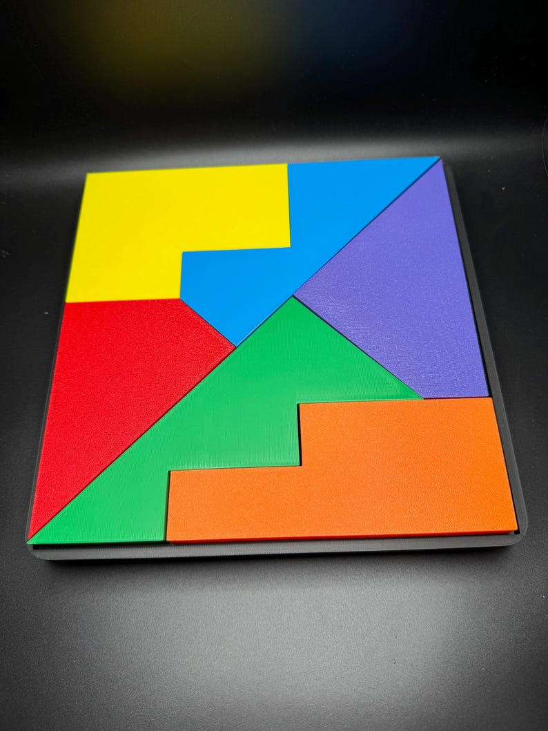 May include: A wooden puzzle with seven pieces in different colors: yellow, blue, red, green, orange, and purple. The pieces fit together to form a square.