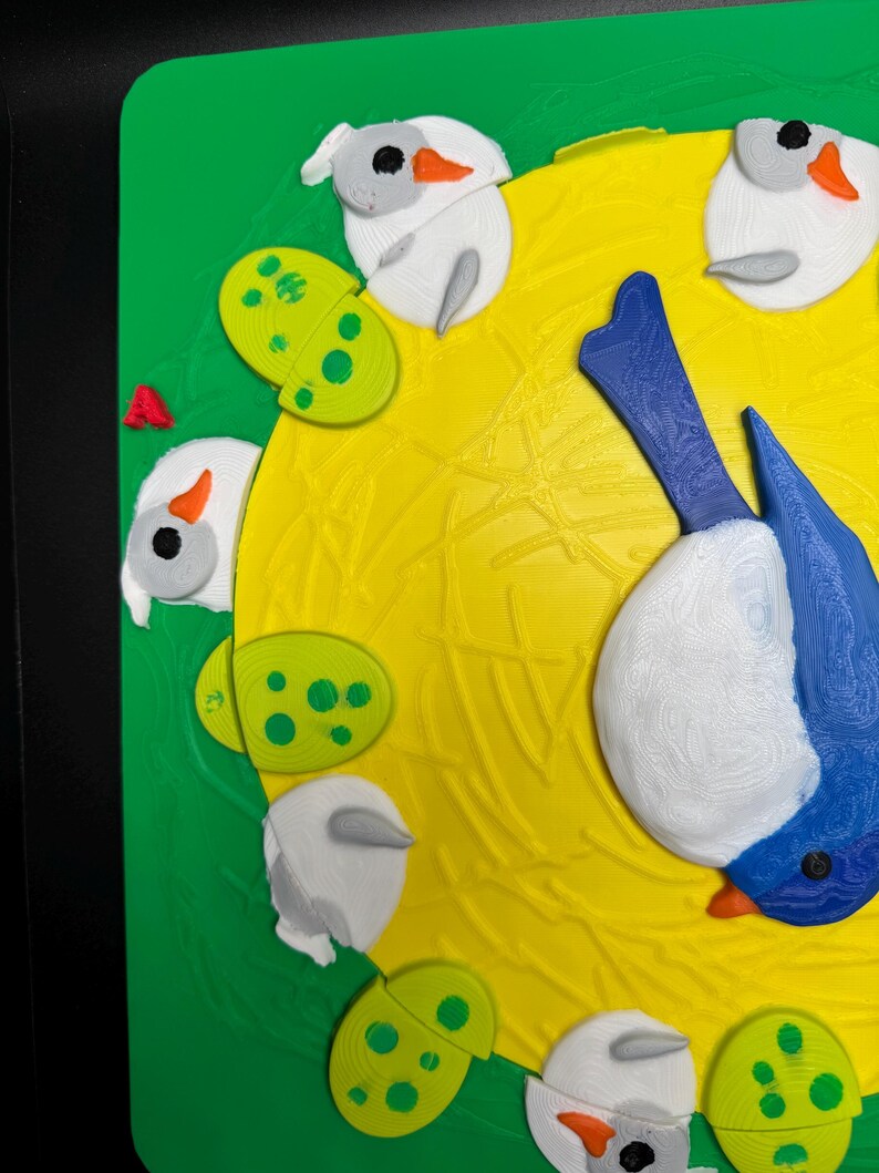 May include: A colorful 3D-printed artwork featuring a blue and white bird with an orange beak, surrounded by white bird-like shapes and green, spotted, oval shapes. The background is yellow and green.