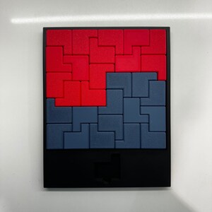 Puede incluir: Un juego de rompecabezas negro con un dise&ntilde;o rojo y azul. El rompecabezas est&aacute; formado por peque&ntilde;os cuadrados que encajan para crear una imagen m&aacute;s grande.