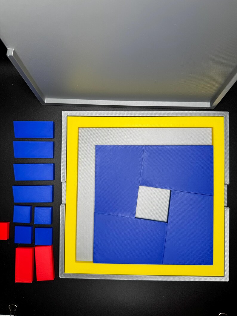 May include: A blue and yellow puzzle box with a silver frame. The puzzle box is open and the puzzle pieces are arranged in a spiral pattern. The puzzle pieces are blue, yellow, and silver.