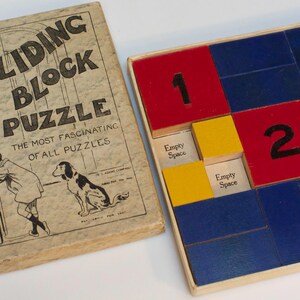 May include: A wooden game box with a sliding block puzzle. The box is brown with a white label that reads "Sliding Block Puzzle, The Most Fascinating of All Puzzles". The puzzle board is made of wood and has blue, red, and yellow squares with numbers 1, 2, and 3.