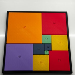 Peut inclure: Un puzzle carr&eacute; compos&eacute; de 10 tuiles color&eacute;es, chacune avec un num&eacute;ro imprim&eacute; dessus. Les tuiles sont dispos&eacute;es selon un motif, la plus grande tuile &eacute;tant dans le coin sup&eacute;rieur gauche et la plus petite dans le coin inf&eacute;rieur droit. Les num&eacute;ros sur les tuiles sont 60, 44, 16, 28, 45, 19, 12, 7, 26 et 33.