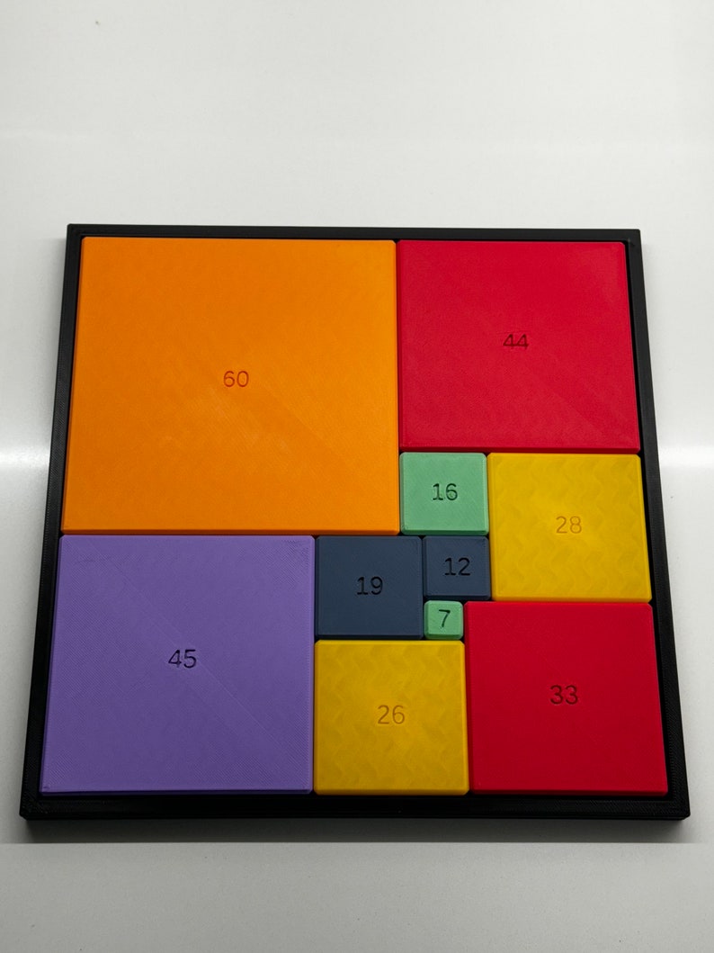 Peut inclure: Un puzzle carr&eacute; compos&eacute; de 10 tuiles color&eacute;es, chacune avec un num&eacute;ro imprim&eacute; dessus. Les tuiles sont dispos&eacute;es selon un motif, la plus grande tuile &eacute;tant dans le coin sup&eacute;rieur gauche et la plus petite dans le coin inf&eacute;rieur droit. Les num&eacute;ros sur les tuiles sont 60, 44, 16, 28, 45, 19, 12, 7, 26 et 33.