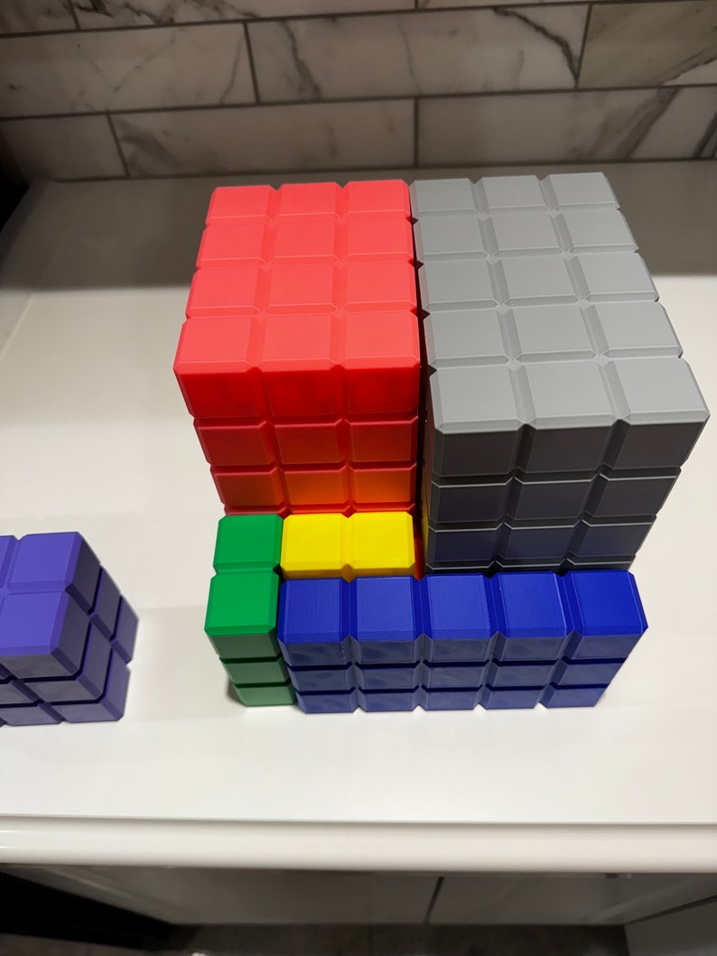 May include: A set of colorful building blocks in red, gray, yellow, green, and blue. The blocks are stacked on top of each other to form a tower.