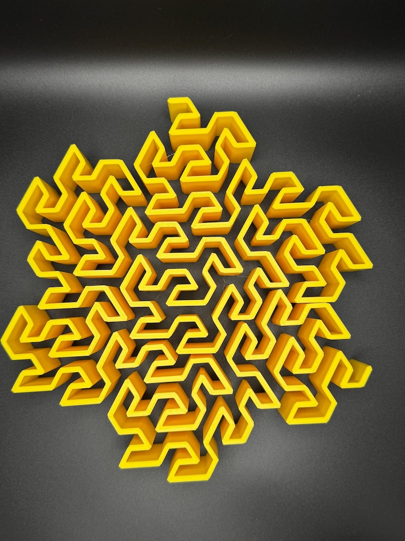 May include: A yellow 3D printed maze in the shape of a star. The maze is made up of many small, interconnected squares.