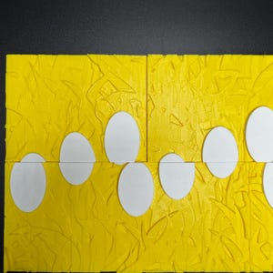 May include: A yellow textured surface with a row of white circles cut out. The circles are arranged in a staggered pattern.