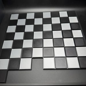 Peut inclure: Un plateau de jeu d'&eacute;checs noir et blanc avec un fond noir. Le plateau est en plastique et a une surface textur&eacute;e.
