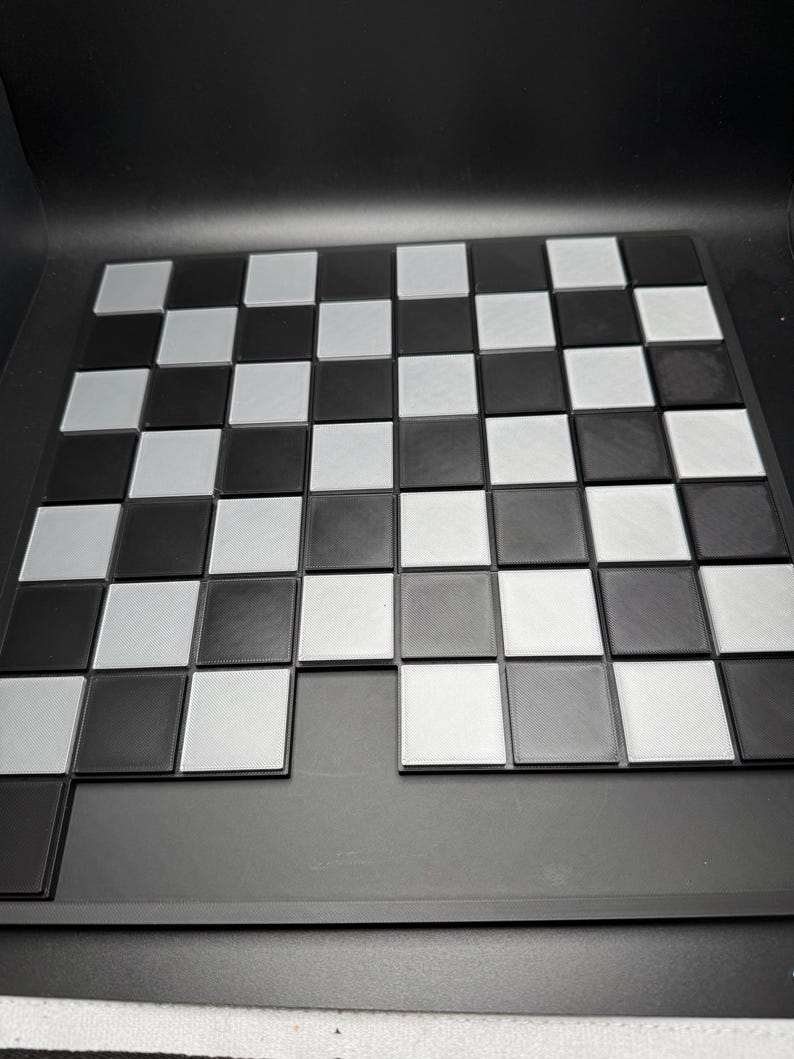 Peut inclure: Un plateau de jeu d'&eacute;checs noir et blanc avec un fond noir. Le plateau est en plastique et a une surface textur&eacute;e.