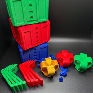 May include: A set of colorful 3D printed building blocks, including green, red, blue, yellow, and orange pieces. The blocks are stacked on top of each other, and there are also some smaller pieces, such as brackets and connectors.