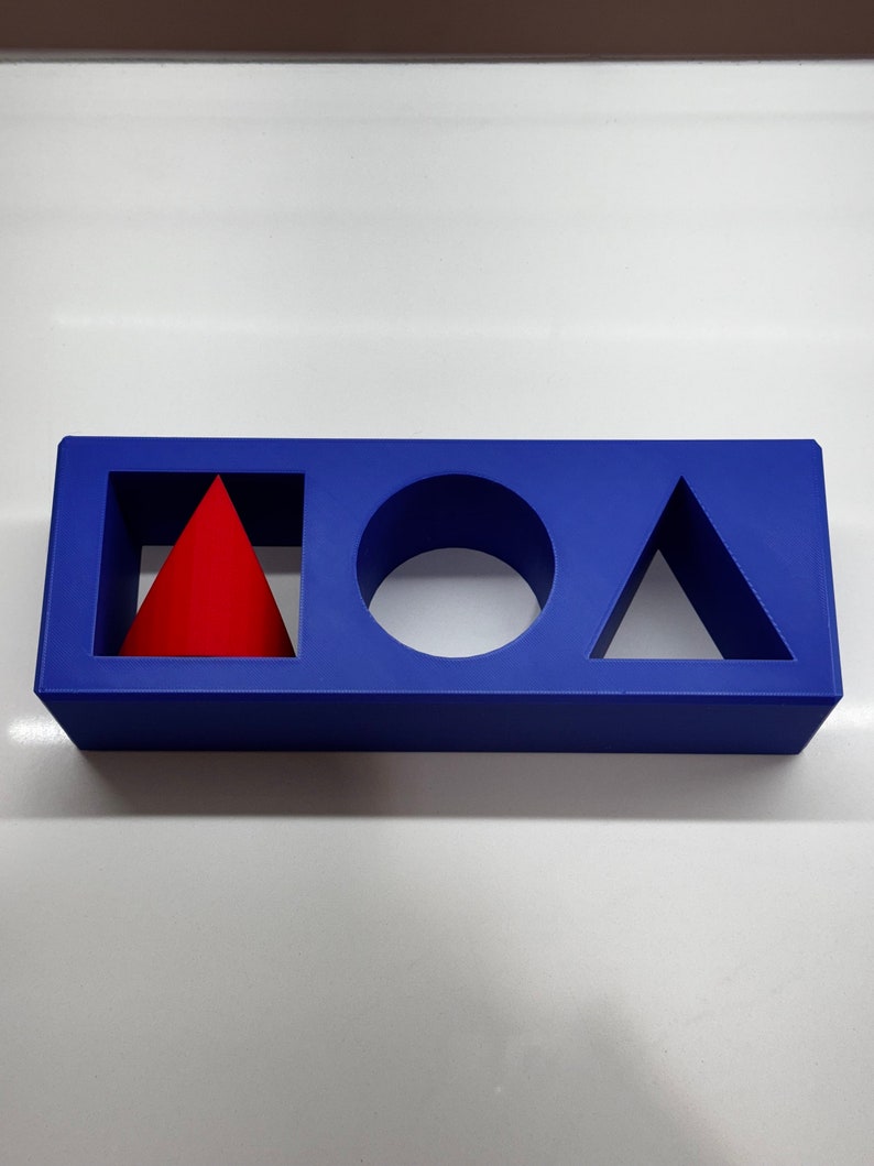 May include: A blue rectangular block with three cutouts. The cutouts are shaped like a square, a circle, and a triangle. A red cone is placed inside the square cutout.