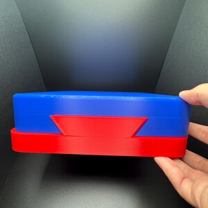 May include: Two stacked, oval-shaped boxes. The top box is blue and the bottom box is red.