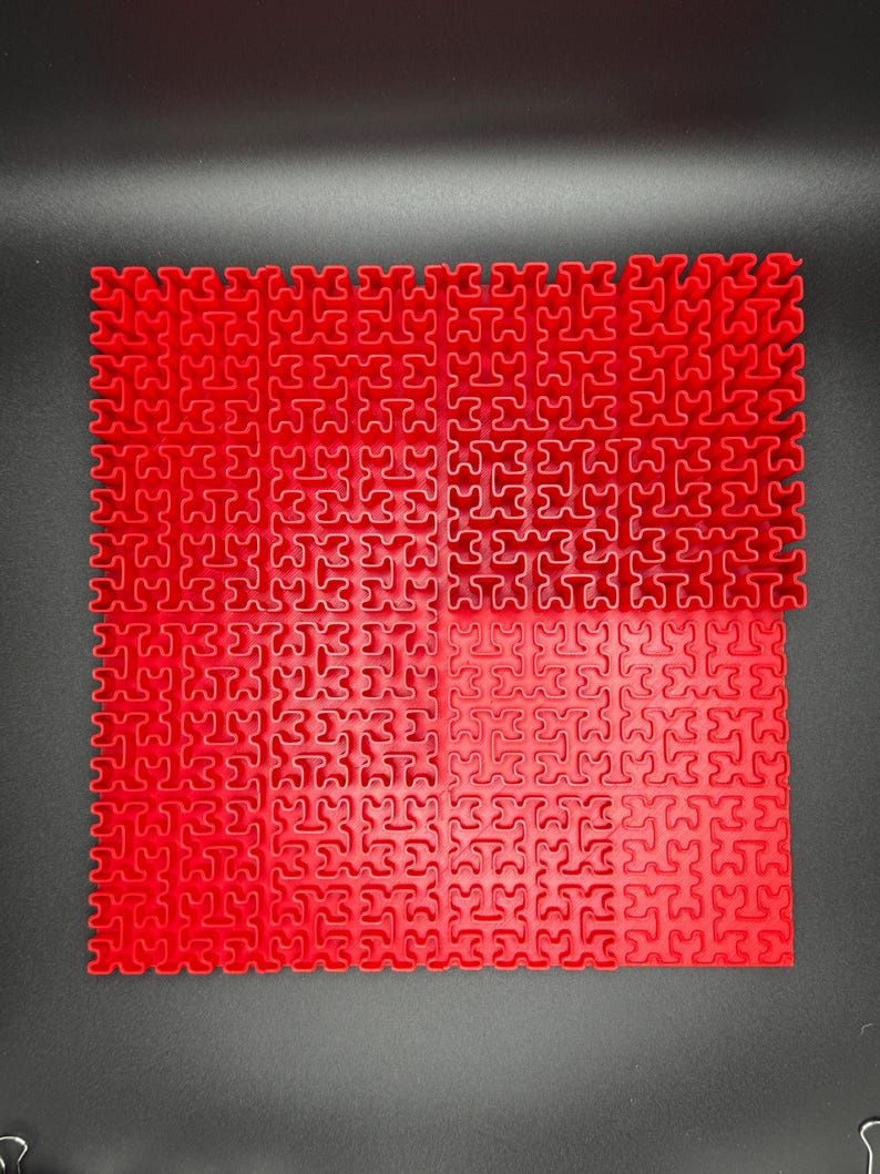 May include: A red interlocking puzzle made of plastic pieces. The puzzle is assembled in a square shape.