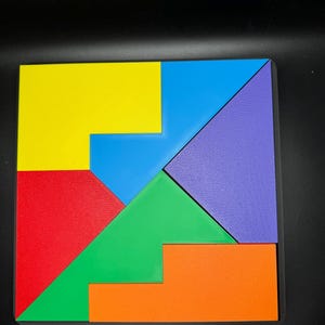 May include: A colorful tangram puzzle with seven pieces in yellow, blue, green, red, purple, and orange. The pieces are arranged to form a square.
