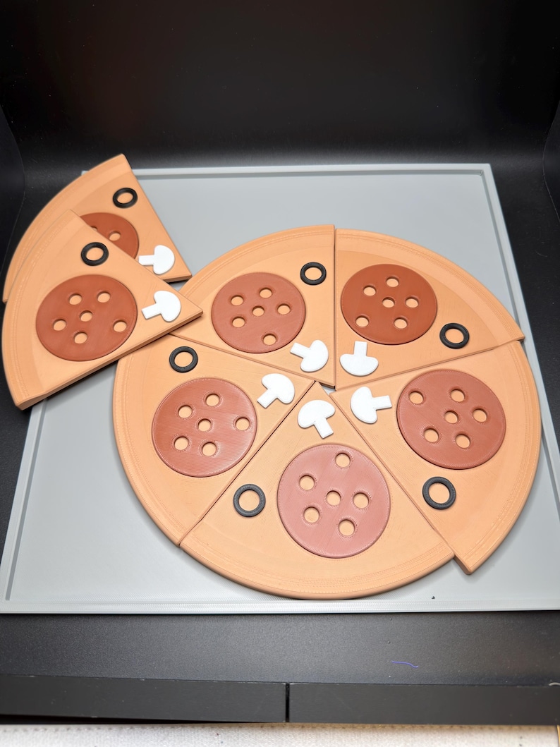 May include: A toy pizza set made of light tan dough-colored material, featuring several triangular slices. Each slice is topped with a brown pepperoni circle with six holes, a small white mushroom piece, and a thin black olive ring.