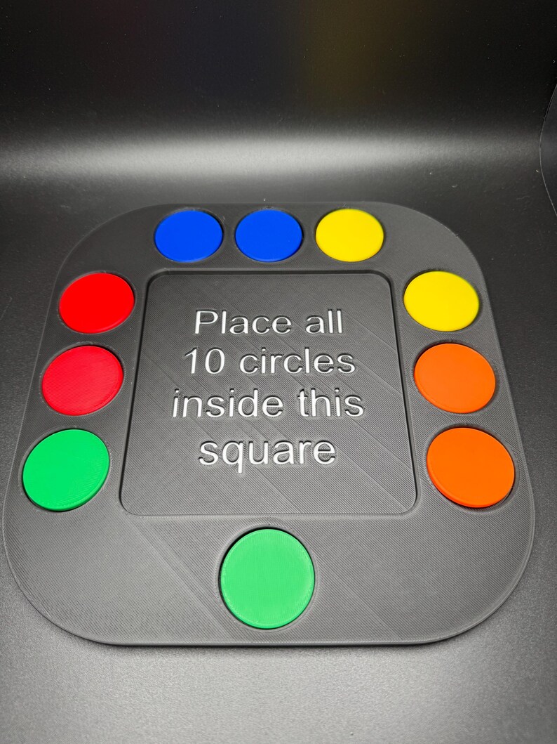 K&ouml;nnte beinhalten: Ein graues Puzzlespiel mit zehn farbigen Kreisen: rot, gr&uuml;n, blau, gelb und orange. Der Text auf dem Spiel lautet: "Platzieren Sie alle 10 Kreise in diesem Quadrat."