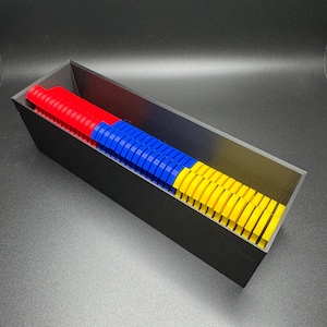 May include: A black rectangular container filled with colorful plastic pieces. The pieces are stacked in three rows, with red on the bottom, blue in the middle, and yellow on top.