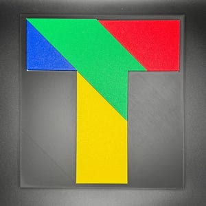 May include: A colorful puzzle shaped like the letter T. The puzzle is made up of four pieces: a red piece, a green piece, a yellow piece, and a blue piece.