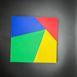 May include: A square puzzle made of five pieces. The pieces are blue, red, green, and yellow. The puzzle is made of foam.