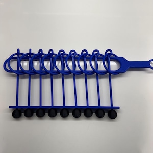 Pode incluir: Uma ferramenta de pl&aacute;stico azul com 10 pontas de borracha pretas. A ferramenta tem uma al&ccedil;a e uma s&eacute;rie de la&ccedil;os que seguram as pontas.