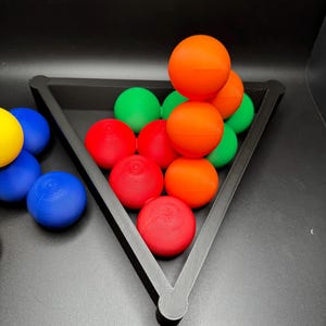 Peut inclure: Un rack triangulaire noir contient une pile de boules color&eacute;es. Les boules sont rouges, orange, vertes et bleues. Les boules sont dispos&eacute;es en forme de pyramide.