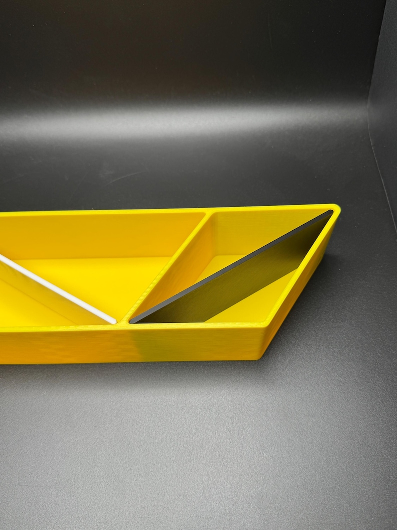 May include: A yellow triangular tray with three compartments. The tray is divided into three sections, with one section being black.