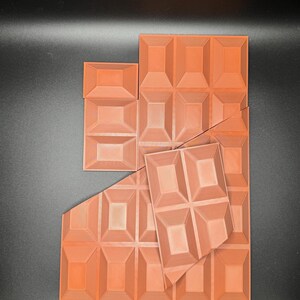 Op de afbeelding: Een set oranje-bruine chocolade vormen. De vormen zijn gemaakt van een getextureerd plastic en hebben een reli&euml;f ontwerp. De vormen zijn in een willekeurig patroon gerangschikt.