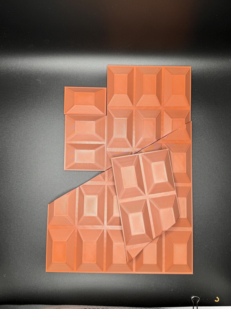 Op de afbeelding: Een set oranje-bruine chocolade vormen. De vormen zijn gemaakt van een getextureerd plastic en hebben een reli&euml;f ontwerp. De vormen zijn in een willekeurig patroon gerangschikt.