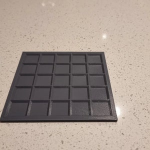 May include: A black plastic grid with 36 square compartments.