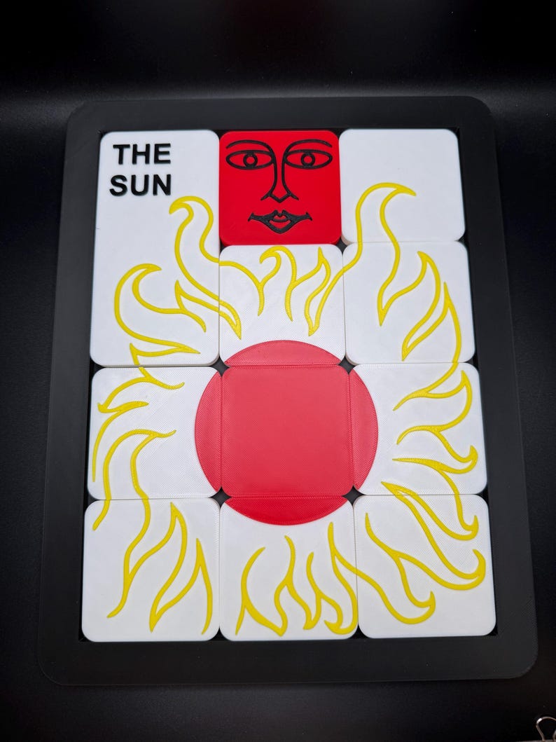 May include: A puzzle featuring the sun tarot card design. The puzzle has a black frame and is composed of white squares with yellow flames and a red sun in the center. The text "THE SUN" is visible on one of the squares.