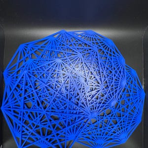 May include: A blue geometric wall art piece made of thin metal wires. The piece is shaped like a circle with a complex pattern of intersecting lines.