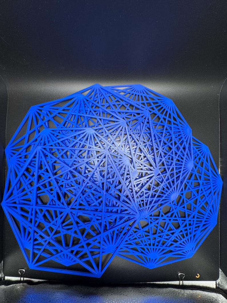 May include: A blue geometric wall art piece made of thin metal wires. The piece is shaped like a circle with a complex pattern of intersecting lines.