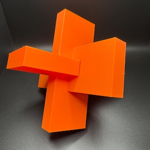 May include: A bright orange geometric sculpture made of four intersecting rectangular prisms.