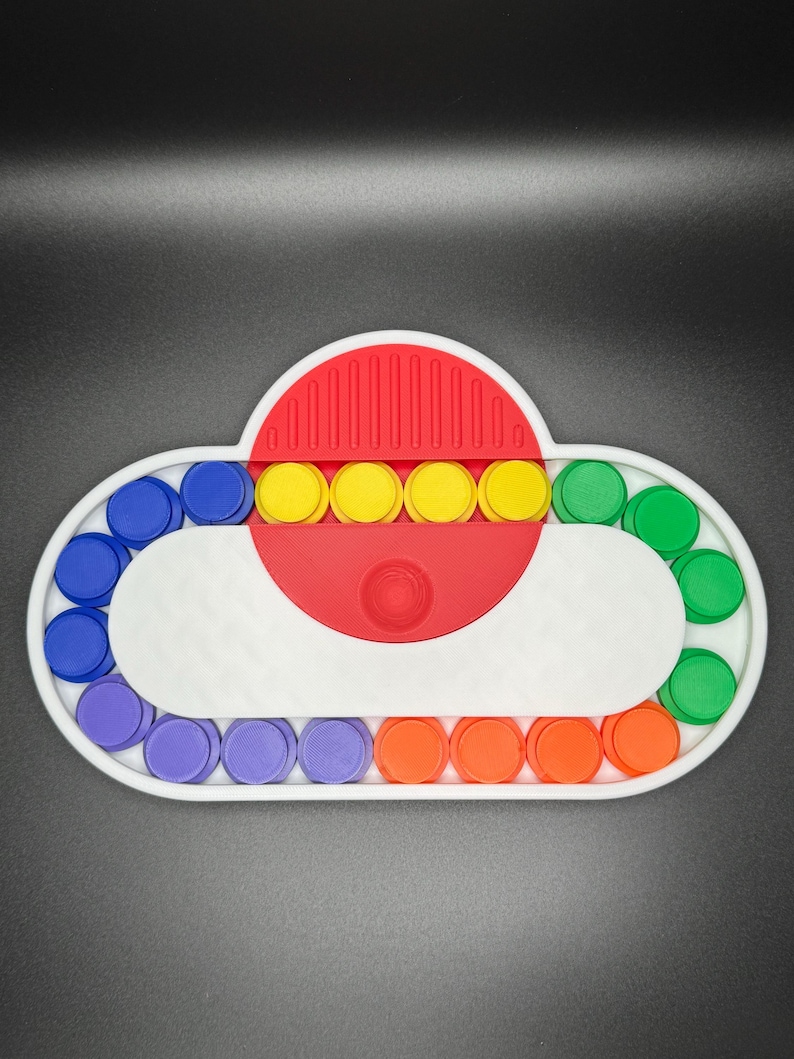 May include: A white cloud-shaped fidget toy with a red center and a row of yellow buttons. The cloud is surrounded by a ring of colorful buttons in purple, blue, green, and orange.