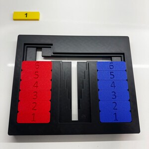 May include: A black puzzle game with two rows of numbered tiles. The tiles on the left are red and the tiles on the right are blue. The numbers 1 through 6 are visible on each side.