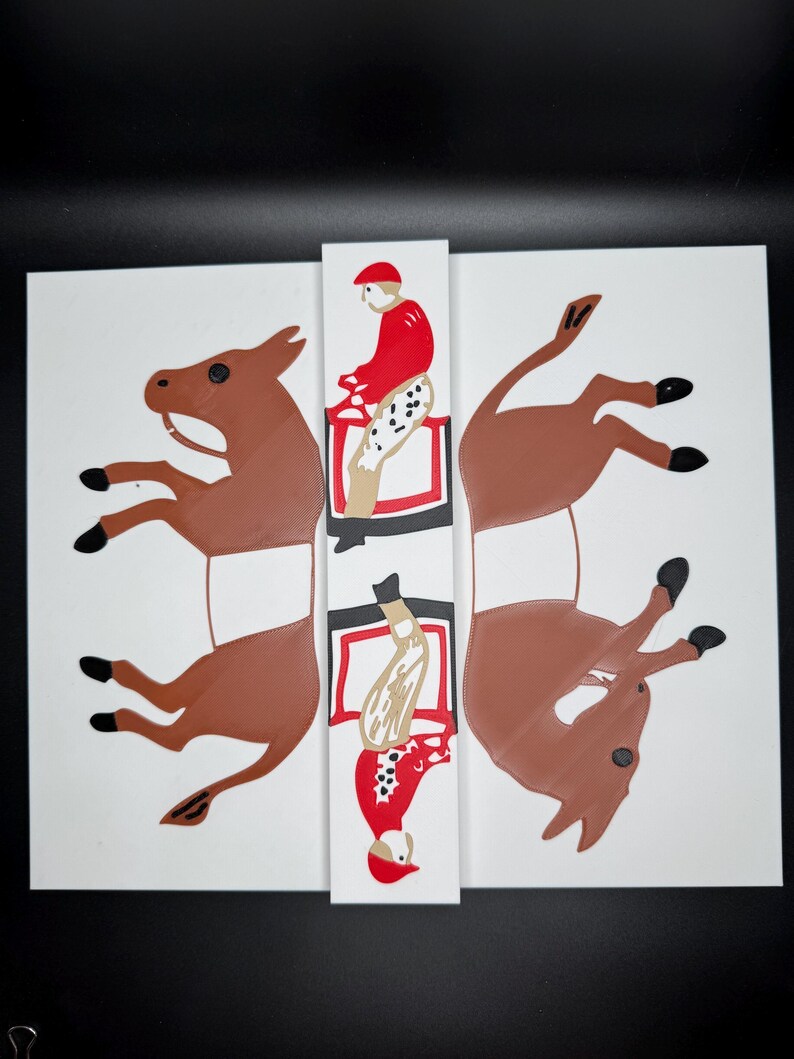 May include: A white paper craft with two brown paper donkeys and two red and white paper figures riding the donkeys. The figures are in a riding position, one is upright and the other is upside down.