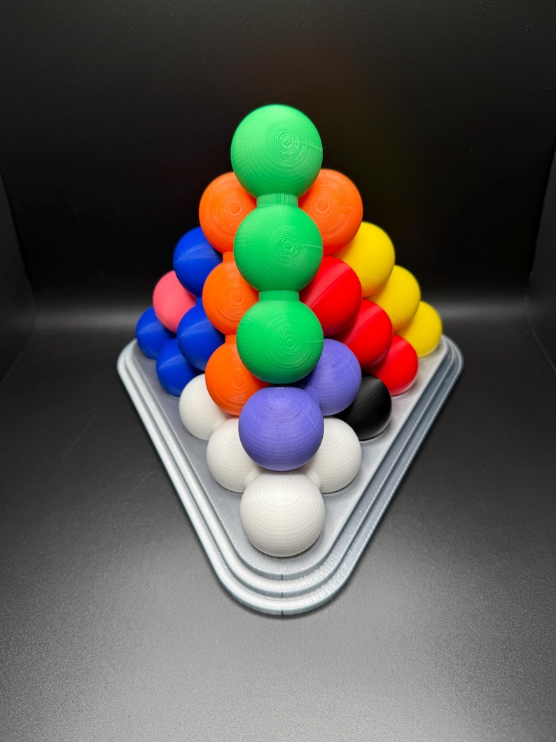 May include: A pyramid-shaped puzzle made of colorful balls. The balls are arranged in a triangular pattern, with the largest ball at the top and the smallest balls at the bottom. The puzzle is made of plastic and is designed to be challenging and fun.