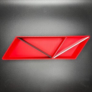 May include: A red, triangular-shaped tray with three compartments. The compartments are divided by black and white dividers. The tray is made of plastic.