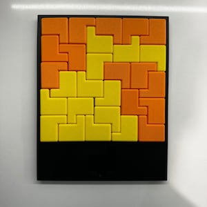 Puede incluir: Un rompecabezas con marco negro con piezas entrelazadas de color naranja y amarillo. El rompecabezas est&aacute; formado por peque&ntilde;os cuadrados que encajan para formar un dise&ntilde;o m&aacute;s grande.